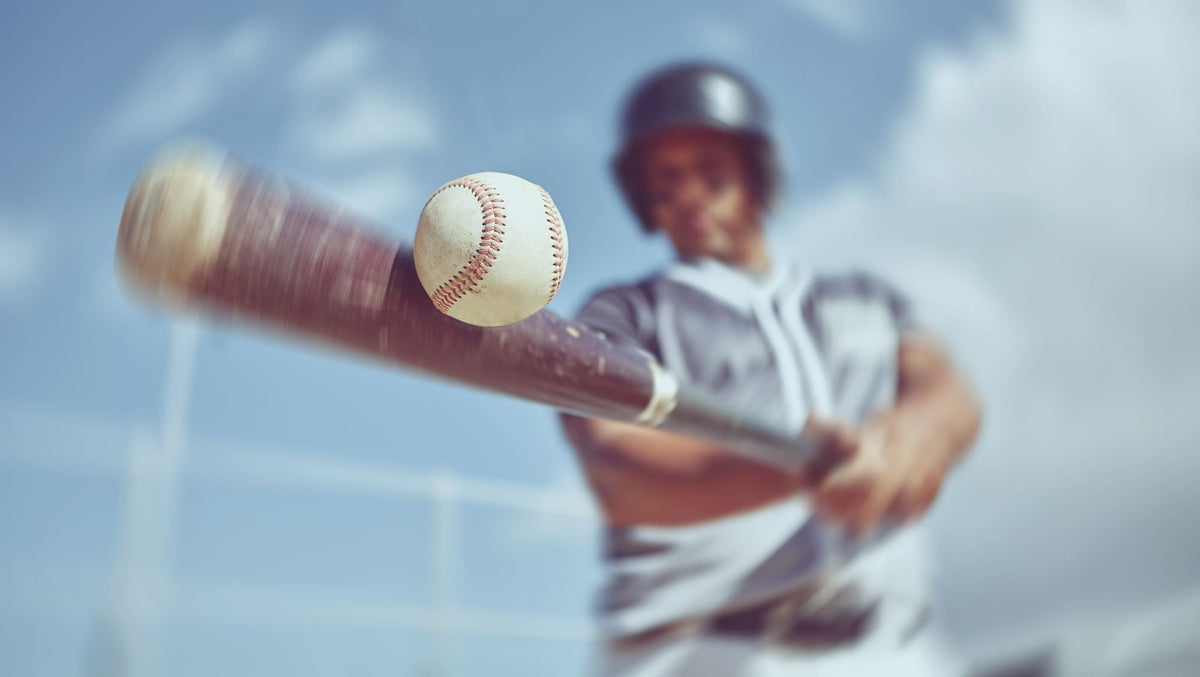 A batter bits a ball from a pitching machine, showing that pitching machines are worth it