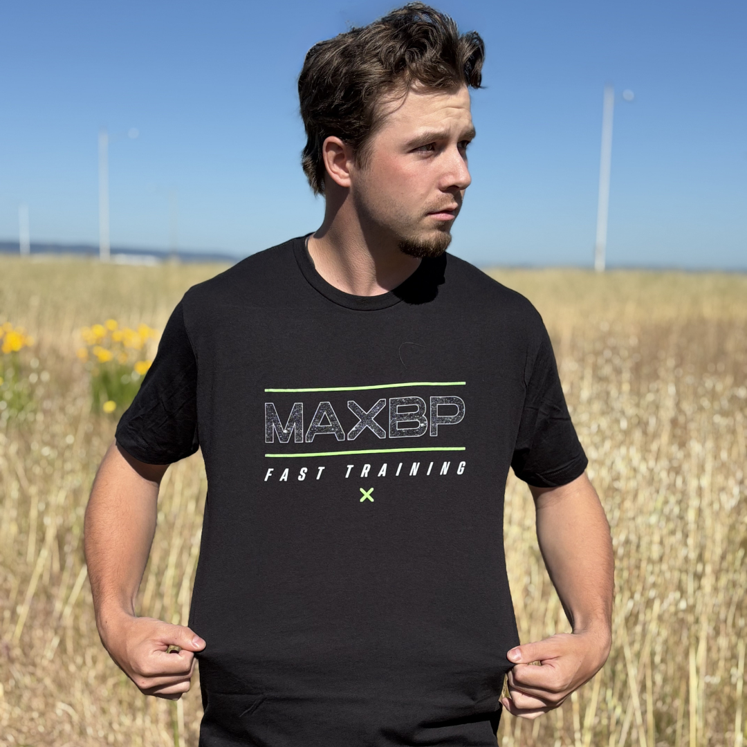 Man wearing a black t-shirt with 'MAXBP' logo in a field