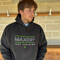 Person wearing a black hoodie with 'MAXBP Fast Training' text against a brick wall.