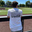 Person wearing a white t-shirt with text at a sports field