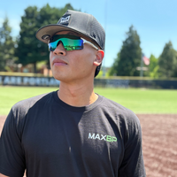 Person wearing a black 'MAXBP' t-shirt on a baseball field