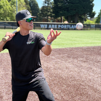 Person playing baseball on a field with 'We Are Portland' banner in the background